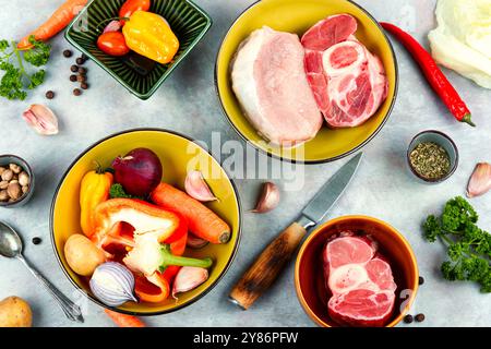 Frisches Fleisch und Gemüse auf dem Küchentisch. Rohe Rinderknochen und Schweinefleisch als Suppe. Draufsicht, flach. Stockfoto