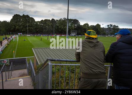 Die Heimfans sehen zu, wie die Heimspieler ihr Eröffnungstor feiern, als Caernarfon Town (in gelb) in einem Europa Conference First q die Crusaders spielt Stockfoto