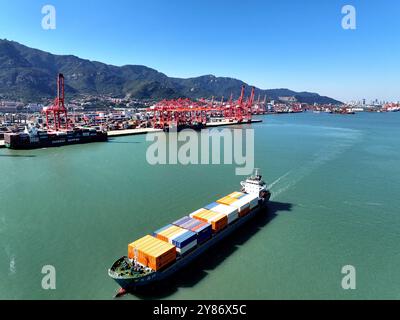 LIANYUNGANG, CHINA - 3. OKTOBER 2024 - Ein mit Containern beladenes Frachtschiff verlässt seinen Liegeplatz am Hafen-Containerterminal in Lianyungang, Ostchina. Stockfoto
