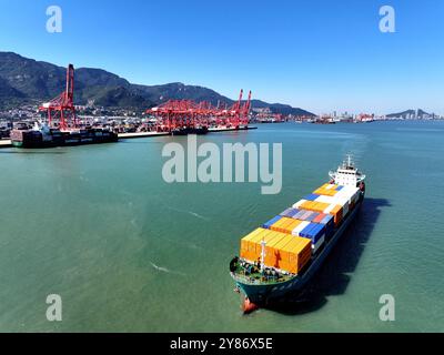 LIANYUNGANG, CHINA - 3. OKTOBER 2024 - Ein mit Containern beladenes Frachtschiff verlässt seinen Liegeplatz am Hafen-Containerterminal in Lianyungang, Ostchina. Stockfoto