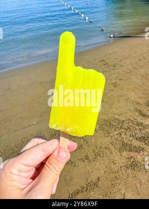 Hand hält gelbe Stiele am Strand. Hochwertige Fotos Stockfoto