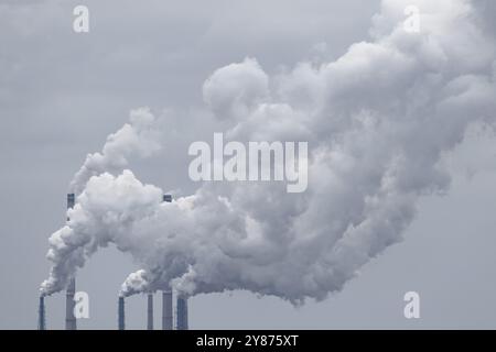 Mehrere Schornsteine eines Kohlekraftwerks geben große Rauchwolken in die Atmosphäre ab, die schwere Industrieluft und Umweltverschmutzung verursachen Stockfoto