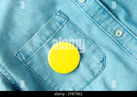 Gelbes Knopfabzeichen am Jeansshirt, Draufsicht. Modell für Design Stockfoto