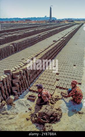 Bangladesch, Dakha, Frauen verwenden eine Form, um Ton zu einem Ziegel zu Formen, den sie auf der Baustelle trocknen lassen. Stockfoto