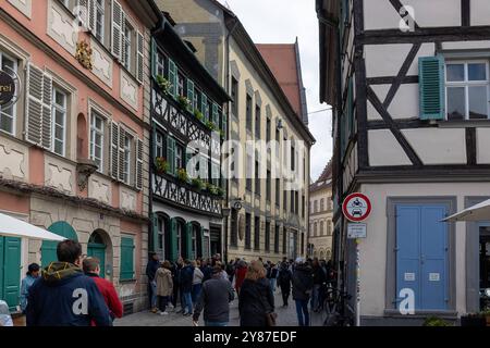 Bamberger Stadtblick, 03.101.2024 das Bild zeigt die belebte Sandstraße in Bamberg mit der historischen Brauerei Schlenkerla auf der linken Seite, erkennbar an den Fachwerkhäusern und traditionellen Fensterläden. Menschen schlendern durch die schmale Gasse, die von bunten, historische Gebäude gesäumt ist. Die Szenerie vermittelt das typische Flair der Altstadt von Bamberg, geprägt von Touristen und Einheimischen, die Architektur und die lokale Gastronomie genießen. Bamberg Bayern Deutschland *** Bamberger Stadtansicht, 03 101 2024 das Bild zeigt die lebhafte Sandstraße in Bamberg mit dem Hi Stockfoto