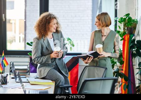 Zwei Kollegen teilen einen freudigen Moment bei einem Kaffee und diskutieren Ideen in einem integrativen Arbeitsbereich. Stockfoto