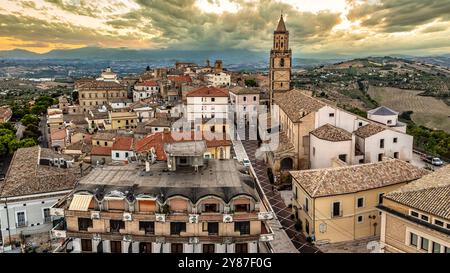 Aus der Vogelperspektive auf die mittelalterliche Stadt Città Sant'Angelo, beleuchtet durch den Sonnenuntergang, im Vordergrund die Stiftskirche San Michele Arcangelo. Stockfoto