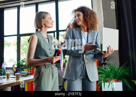 Zwei Kollegen teilen einen freudigen Moment in einem lebhaften Büro, wodurch Gemeinschaft und Inklusion geschaffen werden. Stockfoto