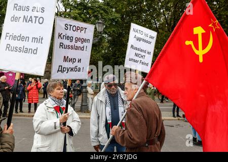 Demo nie wieder Krieg Demonstranten halten Plakate mit Parolen wie Stoppt Krieg gegen Russland , raus der NATO , NATO ist der Aggressor während sie mit einem Mann in russischer Uniform, die eine Flagge der Sowjetunion hält, sprechen, während der Demonstration des Bündnis nie wieder Krieg in Berlin, 03.10.2024. Die Teilnehmer sind gegen die Stationierung von US-Raketen in Deutschland, gegen den Krieg in der Ukraine und gegen deutsche Waffenlieferungen an die Ukraine und Israel. Berlin Berlin Deutschland *** Demonstration nie wieder Krieg Demonstranten halten Plakate mit Slogans wie Stop Stockfoto