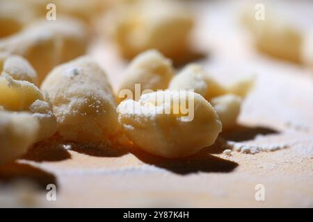 Hausgemachte Kartoffelgnocchi auf Holzbrett und Mehl Stockfoto