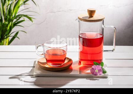 Rote Fruchtaufguss in Kristallglas und Krug auf Holzsockel. Stockfoto