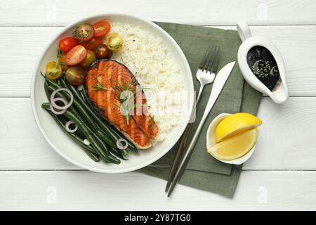 Leckeres gegrilltes Lachssteak mit Reis und Gemüse serviert mit Sojasauce auf weißem Holztisch, Blick von oben Stockfoto