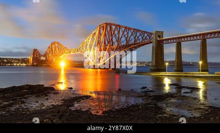 Die Forth Bridge beleuchtete nachts und wurde im 19. Jahrhundert für den Bahnverkehr von South Queensferry in Schottland gebaut Stockfoto