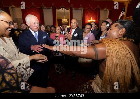 König Karl III. Reagiert, als der ehemalige samoanische Rugbyspieler Freddie Tuilagi bei einem Empfang im St. James's Palace tanzt, der die Commonwealth Diaspora feiert. Stockfoto