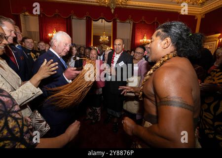 König Karl III. Reagiert, als der ehemalige samoanische Rugbyspieler Freddie Tuilagi bei einem Empfang im St. James's Palace tanzt, der die Commonwealth Diaspora feiert. Stockfoto