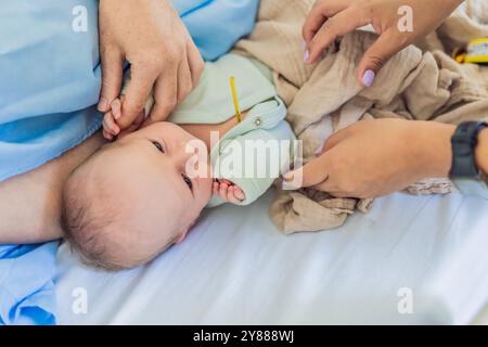 Eine Krankenschwester misst die Temperatur eines Babys im Krankenhaus. Das sanfte und sorgfältige Verfahren sorgt für Komfort und Wohlbefinden des Babys, was es ermöglicht Stockfoto