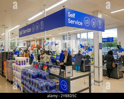 Leute, die für ihren Einkauf an den Selbstbedienungskassen in einem Tesco-Supermarkt, Großbritannien, bezahlen Stockfoto