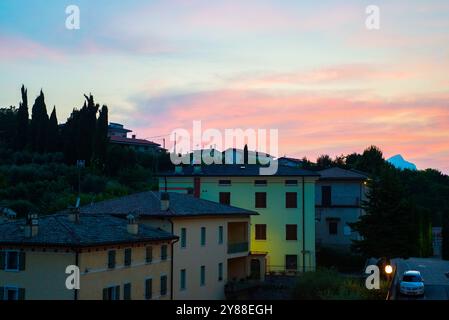 Wunderschöner Abendblick auf rosa bis rote Wolken über traditionellen italienischen Häusern in Costermano sul Garda, Italien Stockfoto