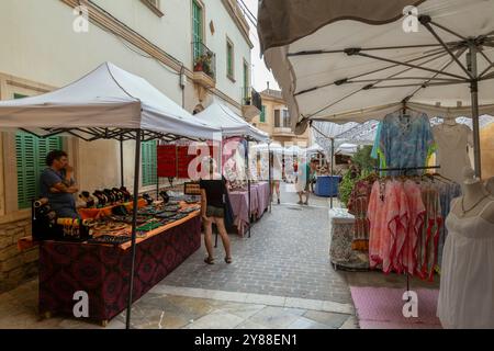 In der malerischen Stadt Santanyí auf Mallorca in Spanien schlendern die Menschen über eine gemütliche, enge Straße, die von Verkaufsständen gesäumt ist. Stockfoto