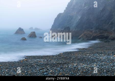 Wilder und geheimnisvoller Strand Trá-na-mBó, Bunmahon, Irland – die felsige Küste in Fog and Mist sorgt für eine unüberirdische Atmosphäre Stockfoto