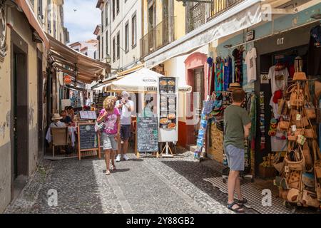 Die Leute laufen durch die gemütliche Santa Maria Straße mit Geschäften, Bars und Restaurants in der Altstadt von Funchal. Stockfoto