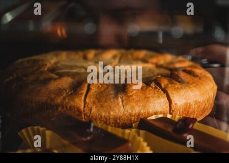 Chicken Pie Vorderansicht Nahaufnahme. Vitrine mit einer Vielzahl von Kuchen und Cupcakes. Schokoladensüten mit Kirsche auf der Spitze. Die Kuchen sind angeordnet Stockfoto