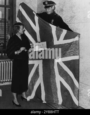 Union Jack von der U.S. Mint -- Mrs. Alma K. Schneider, Direktorin der Denver Mint., und Wachkapitän Jack Carlson zeigen einen selbstgemachten Union Jack, der neun Minuten über die Münzstätte flog, bevor sie von einem Wachmann entdeckt wurde. Mrs. Schneider hält auch ein Schloss, mit dem die britische Flagge am Sonntag auf der Pole befestigt wurde, und eine Notiz, auf der stand: "Einfach aufladen -- Winnie." November 1953. (Foto von AP Wirephoto). Stockfoto