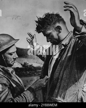 Britischer Soldat durchsucht in Tunesien Deutsch -- Ein Soldat der British First Army durchsucht einen deutschen Gefangenen, der bei den Kämpfen in der Nähe von Sedjenane in Nordtunesien gefangen genommen wurde. Juli 1943. Stockfoto