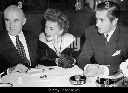 Die Tyrone Powers Im Stork Club. Tyrone Power (rechts), der in New York an der Weltpremiere seines neuesten Films „The Razor's Edge“ teilnimmt, hört interessanterweise einer Anekdote von Samuel Goldwyn (links) zu, als Power und seine Frau Annabella (Mitte) am 16. November den Stork Club in New York besuchen. Power bestätigte am 26. Oktober eine Ankündigung, dass er und seine Frau sich getrennt hätten, bestritt jedoch Berichte, dass er Gene Tierney heiraten würde, mit dem er in The Razor's Edge mitgespielt wird. November 1946. (Foto von zugehörigem Pressefoto). Stockfoto