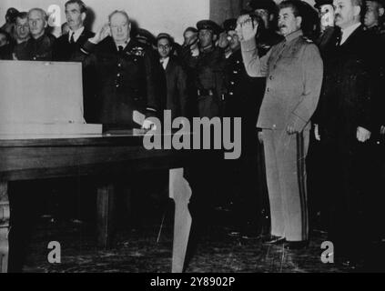 Churchill präsentiert Stalin auf der Teheran-Konferenz Memorial Sword – vor einer Gruppe militärischer und diplomatischer Helfer, dem britischen Premierminister Winston Churchill (links) und dem russischen Premierminister Joseph Stalin Salute, als die russische Nationalhymne während der Zeremonien gespielt wird, bei denen Churchill Marschall Stalin ein Schwert (falls auf dem Tisch) überreichte, das den Helden gewidmet war, die Stalingard verteidigten. Die Zeremonie fand in der russischen Botschaft in Teheran, Iran, statt, als die beiden alliierten Führer und der US-Präsident Franklin D. Roosevelt Pläne zur Niederschlagung der deutschen Streitkräfte fertigstellten. Be Stockfoto