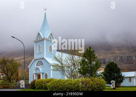 Die Blaue Kirche in Seydisfjordur (Seydisfjardarkirkja), Außenansicht der hellblauen Gebäudefassade mit grüner Vegetation rund um Island. Stockfoto