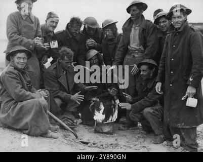 Während der Fahrt, die die 8. Armee von Ägypten bis an die Grenzen von Tripolis führte, wurden alle Arten von Wetter erlebt. Blendender Staub wich dem Regen, der die Wüste in einen Sumpf verwandelte. Hier ist eine Gruppe fortgeschrittener britischer Truppen, die sich um ein "tragbares" Feuer warfen. Februar 1943. (Foto vom Department of Information, Commonwealth of Australia). Stockfoto