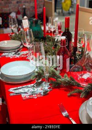 Der festliche Weihnachtstisch ist mit festlichen Dekorationen geschmückt und bereit für ein fröhliches Treffen im Winter. Leuchtend rote Tischdecke und elegantes Geschirr Stockfoto