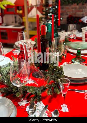 Der festliche Weihnachtstisch ist mit festlichen Dekorationen geschmückt und bereit für ein fröhliches Treffen im Winter. Leuchtend rote Tischdecke und elegantes Geschirr Stockfoto