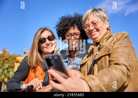 Gruppe von verschiedenen reiferen Frauen, die lächeln und ihr Smartphone benutzen Stockfoto