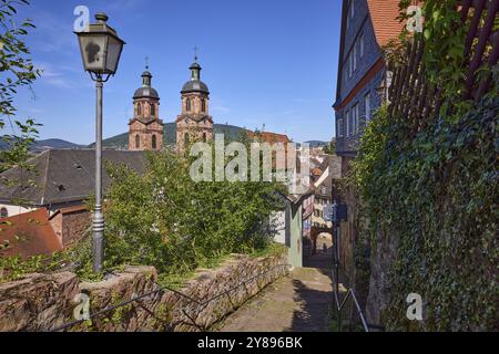 Laterne und Türme der Pfarrkirche St. Jakob gegen den blauen Himmel von den Steinstufen der Schlossgasse in Miltenberg, Unterfranken, dist Stockfoto