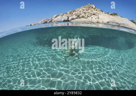Junge Frau schwimmt am Boden eines exotischen Strandes mit halber Unterwassersicht Stockfoto