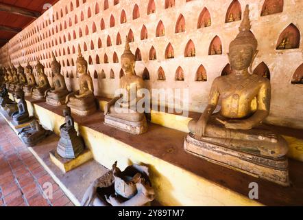 Große goldene, sitzende Buddha-Statuen vor kleinen Wandnischen mit kleiner Buddha-Statue im Inneren. Im Wat Sisaket in Vientiane, Laos Stockfoto