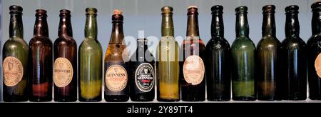 Reihe alter, antiker, Vintage- und Sammlerflaschen von Guinness in verschiedenen Farben und mit verschiedenen Etiketten. Stockfoto