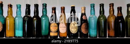 Reihe alter, antiker, Vintage- und Sammlerflaschen von Guinness in verschiedenen Farben und mit verschiedenen Etiketten. Stockfoto