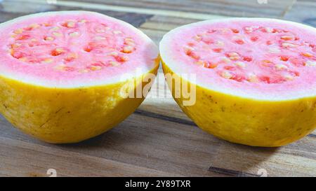 Eine Guava, die in zwei Hälften geschnitten wurde, auf einem Holzschneidebrett. Tropische Früchte. Stockfoto