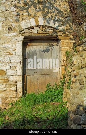 Eine Holztür in einem verlassenen historischen Steinhaus im Gorica-Viertel von Berat in Albanien. Berat ist ein UNESCO-Weltkulturerbe Stockfoto