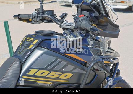 Nahaufnahme eines suzuki V strom 1050 Motorrads, das auf einer Asphaltstraße geparkt ist und dessen Tank, Lenker und Branding hervorhebt Stockfoto