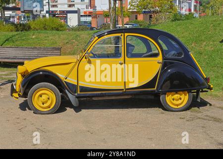 Ein individueller, klassischer citroen 2-cv-Wagen mit gelber und schwarzer Lackierung steht auf einer Straße Stockfoto