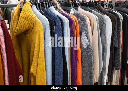 Damenbekleidung – Herbst Winter Kollektion. Modische Strickkleidung, hängend an Regalen zur Ausstellung. Lässige Damen-Pullover, Angebotssaison. Mehrfarbiges W Stockfoto