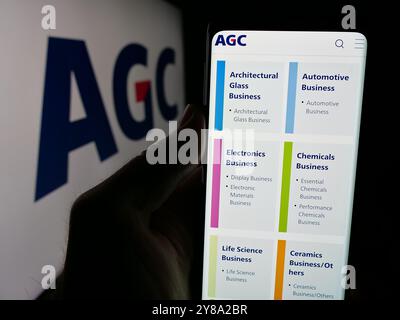 Person, die ein Handy hält, mit einer Webseite der japanischen Glasfabrik AGC Inc. Auf dem Bildschirm mit Logo. Konzentrieren Sie sich auf die Mitte des Telefondisplays. Stockfoto