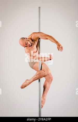 Muskulöser männlicher Stabtänzer hält anmutig eine Pose und zeigt seine Stärke und Flexibilität Stockfoto