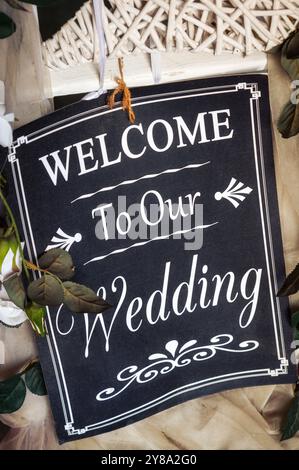 Hochzeitsankündigung auf schwarzem Schild mit weißem Schriftzug, der an einer weißen Korbdekoration hängt Stockfoto