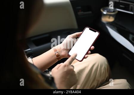 Nahaufnahme Frau, die in einem Auto sitzt und ein Smartphone mit leerem weißen Bildschirm hält Stockfoto