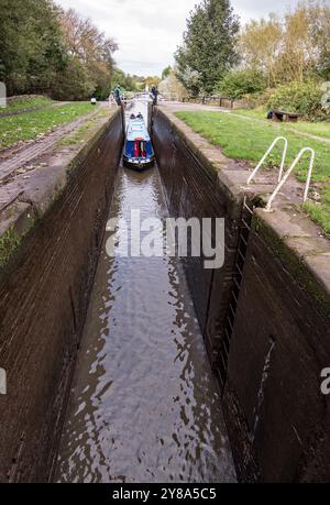 Schmalboot überquert eine tiefe Schleuse auf dem Trent & Mersey Kanal zwischen Kings Lock & Big Lock Pub. Stockfoto